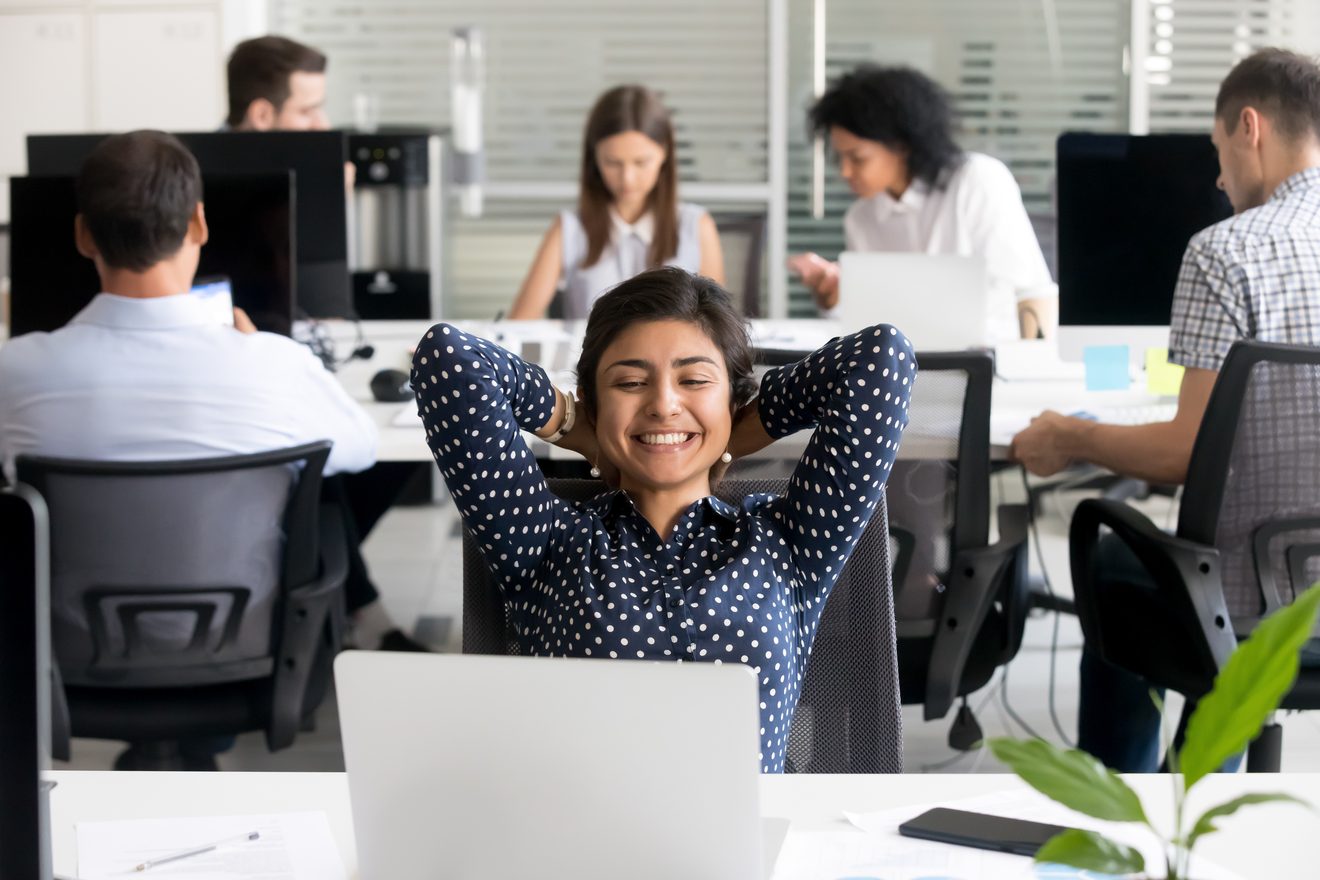 Équipe en open space, une collaboratrice détendue devant son poste de travail